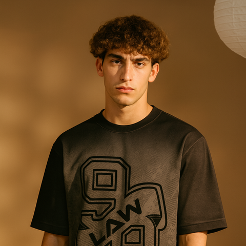 Person wearing a black t-shirt with a logo on a brown background